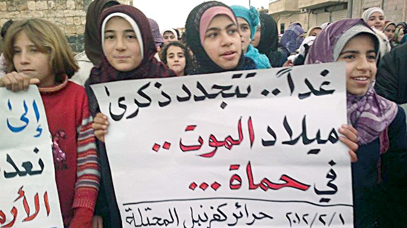In this citizen journalism image provide by the Local Coordination Committees in Syria and released on Wednesday Feb. 1, 2012, an anti-Syrian regime protester, holds an Arabic poster as she walks during a demonstration in Idlib Province, north Syria. (AP / Local Coordination Committees in Syria)