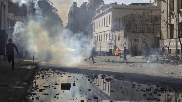 Egyptian protestors run from tear gas fired by security forces during clashes near the Interior Ministry in Cairo, Egypt, Friday, Feb. 3, 2012. (AP Photo/Muhammed Muheisen)