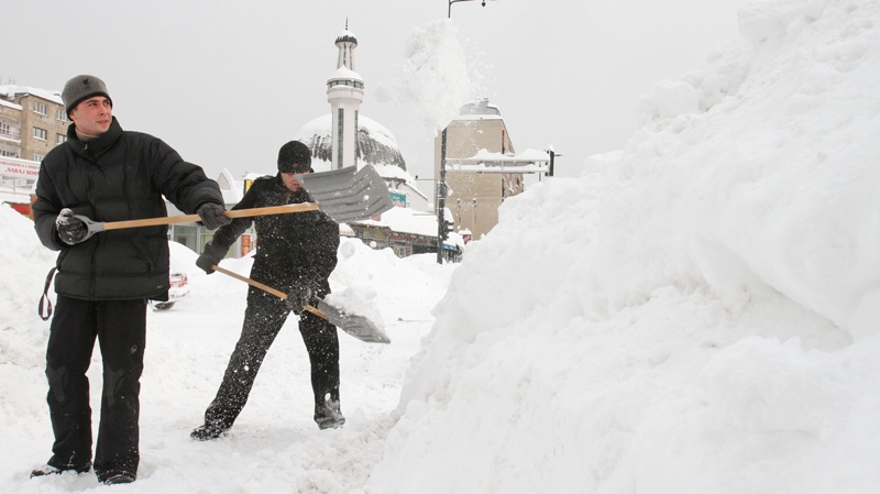 Bosnian men shovel deep snow to clear the path for pedestrians, in the Bosnian capital of Sarajevo, on Saturday, Feb. 4, 2012. (AP / Amel Emric)