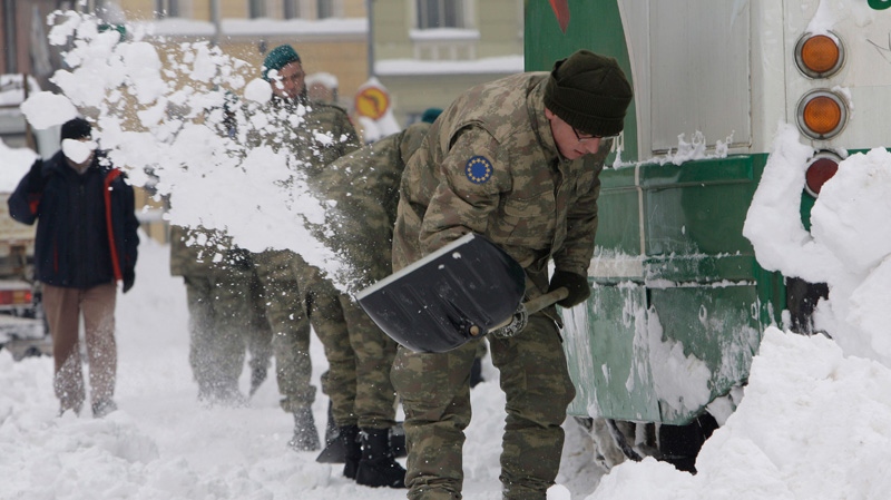 Turkish soldiers members of the European Union Force in Bosnia and Herzegovina, EUFOR shovel snow from the tracks beneath a frozen tram as they working to normalize public transport in Bosnian capital of Sarajevo, on Sunday, Feb. 5, 2012. (AP / Amel Emric)