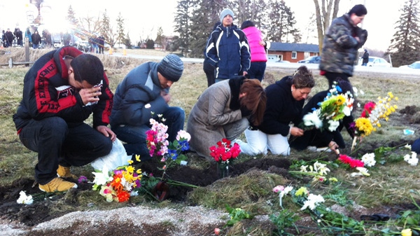 Family and friends place flowers at the scene of the fatal van crash in Hampstead, Ont., on Tuesday, Feb. 7, 2012. (Denise Kimmel / CTV News)