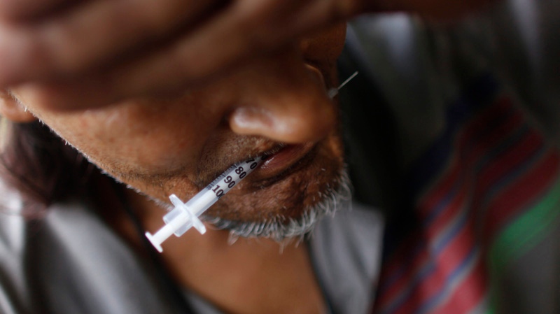 A heroin addict holds a used syringe in his teeth after shooting up in an abandoned lot in San Juan, Friday, July 31, 2009. Some of the South American heroin trafficked through Puerto Rico en route to the United States is sold locally, which has led to an island-wide epidemic, according to health and law enforcement officials. (AP Photo/Brennan Linsley)