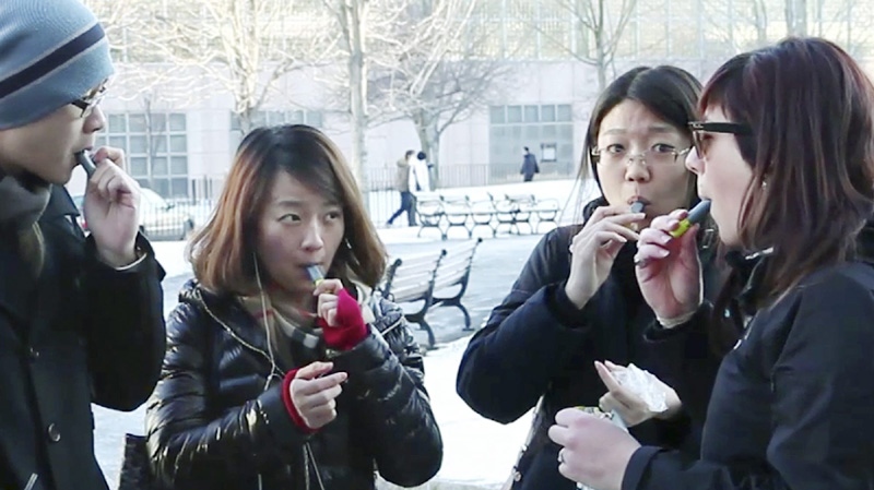 In this Monday, Jan. 23, 2012 still photo taken from video, students try free samples of AeroShot, an inhalable caffeine packed in a lipstick-sized canister, on the campus of Northeastern University in Boston. 