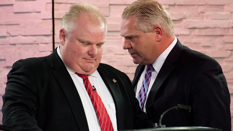 Mayor Rob Ford, left, listens to his brother and campaign manager Doug Ford, right, during a commercial break as Rob Ford takes part in a live television mayoral debate in Toronto on Wednesday, March 26, 2014. (Nathan Denette / THE CANADIAN PRESS)