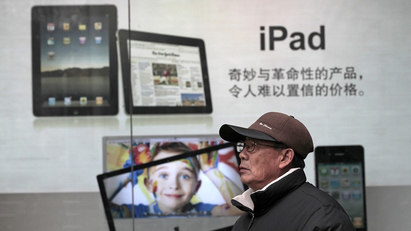 In this file photo taken on Jan. 26, 2011, a man stands near Apple's iPad advertisement in Shanghai, China. (AP Photo/Eugene Hoshiko, File)