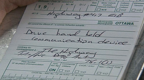 An Ontario Provincial Police officer writes a ticket after nabbing a distracted driver on Feb. 13, 2012.