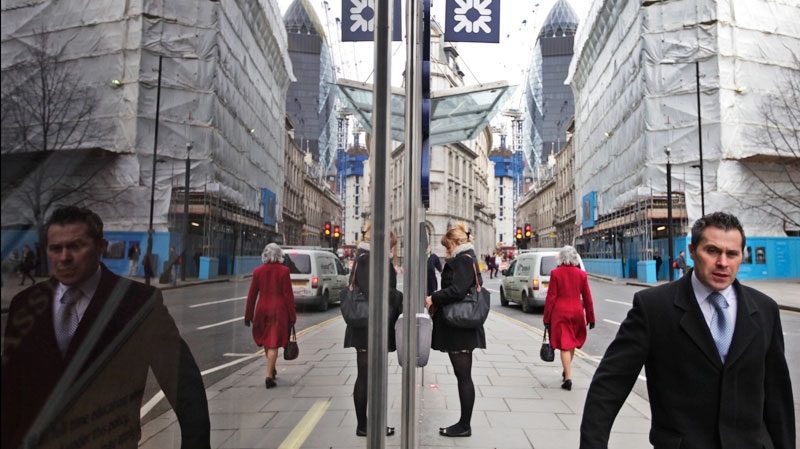 Reflected in a window, people walk in London's City financial district, Tuesday, Feb. 14, 2012. (AP / Lefteris Pitarakis)