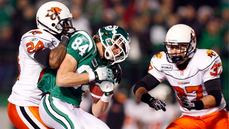 Saskatchewan Roughriders Cary Koch, centre, gets tackled by B.C. Lions Korey Banks, left, as David Hyland looks on during second half CFL Western Semi-Final football action in Regina, Sask., Sunday, Nov. 14, 2010. THE CANADIAN PRESS/Jeff McIntosh