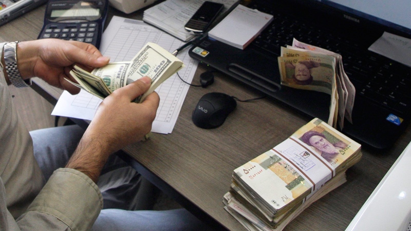 A currency exchange bureau worker counts US dollars, as Iranian bank notes are seen at right with portrait of late revolutionary founder Ayatollah Khomeini, in downtown Tehran, Iran, Wednesday, Dec. 21, 2011. (AP / Vahid Salemi)