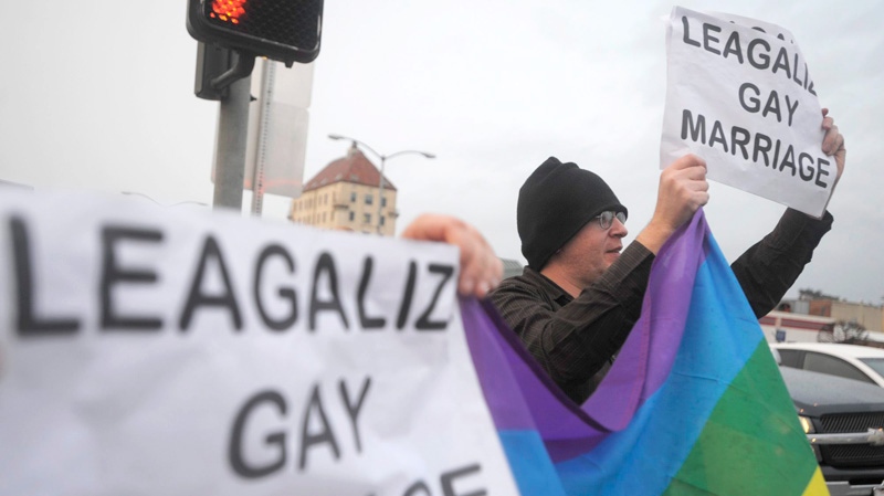 Jeff Giard, right, holds up a rainbow flag in support of same-sex marriage on the corner of Third and E streets as traffic flows through Marysville, Calif. after a federal appeals court declared California's same-sex marriage ban unconstitutional on Tuesday, Feb. 7, 2012. (AP / Appeal-Democrat, Nate Chute)