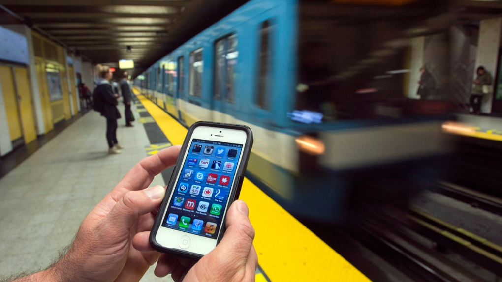 A commuter in Montreal looks at his smart phone