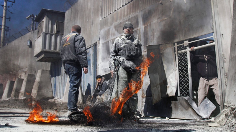 Security guards stand as black smoke rises from tires which were burnt by protesters during an anti-US demonstration in Kabul, Afghanistan, Wednesday, Feb. 22, 2012. (AP / Ahmad Jamshid)