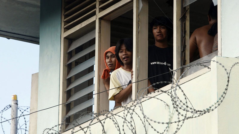Prison inmates occupy the guard's watch tower inside the Kerobokan prison in Denpasar, Bali, Indonesia, Wednesday, Feb. 22, 2012 during a negotiation process after soldiers and policemen controlled most of the prison following a raid. Security forces stormed the prison on Wednesday after rioting inmates temporarily took control of the facility, setting fires and throwing rocks at guards. 