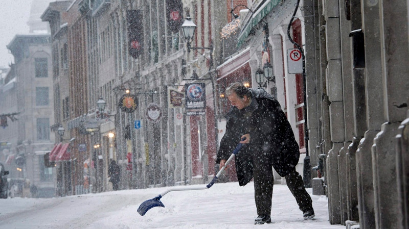 A man shovels the sidewalk in front of his store in Old Montreal during a snowfall Thursday, January 12, 2012. THE CANADIAN PRESS/Paul Chiasson