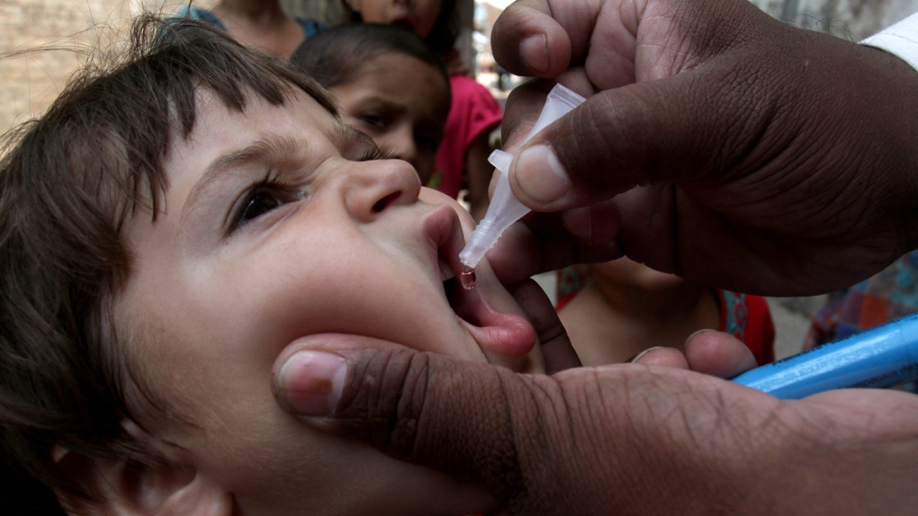 Pakistani health worker gives a polio vaccine