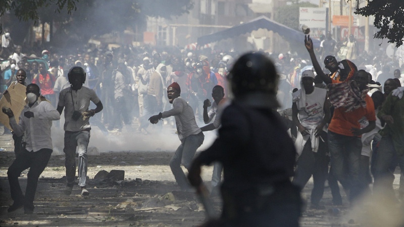 In this Sunday, Feb. 19, 2012 file photo, anti-government protesters throw rocks at police, who respond with tear gas, on a central boulevard in Dakar, Senegal. (AP Photo/Rebecca Blackwell, File)