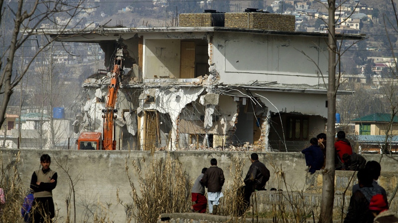 Local residents watch as authorities use heavy machinery to demolish the compound of Osama bin Laden in Abbottabad, Pakistan on Sunday, Feb. 26, 2012. (AP Photo/Anjum Naveed)