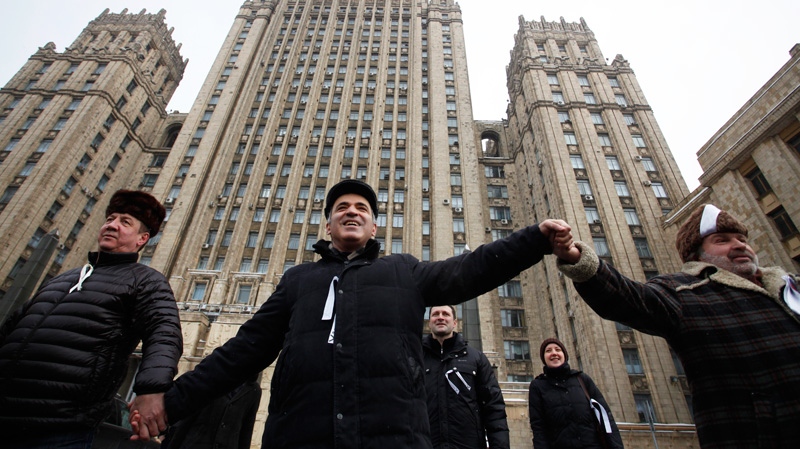 Garry Kasparov, Russian opposition leader and former world chess champion, center, stands holding hands during opposition protest in Moscow Russia, Feb. 26, 2012, with the Russian Foreign Ministry Building in the background. 