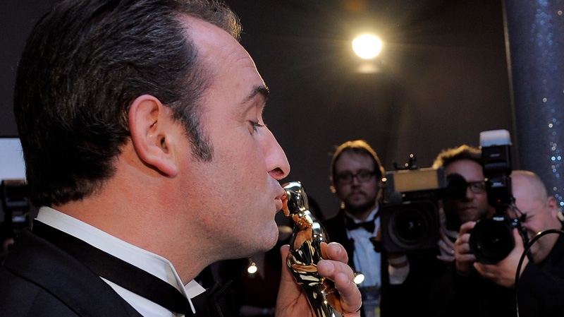 Jean Dujardin, left, kisses his Oscar for best actor in a leading role for "The Artist" after it is engraved at the Governors Ball following the 84th Academy Awards on Sunday, Feb. 26, 2012, in the Hollywood section of Los Angeles. (AP Photo/Chris Pizzello)