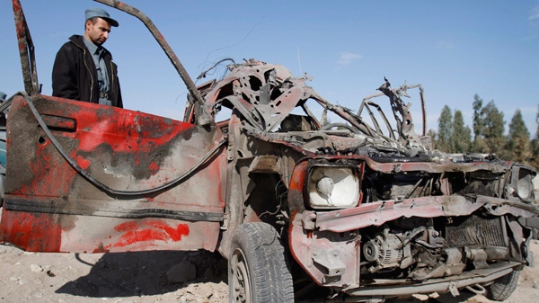 An Afghan police officer inspects a vehicle which was damaged at the scene of a suicide attack at the gate of an airport in Jalalabad, Nangarhar province east of Kabul, Afghanistan, Monday, Feb. 27, 2012. (AP / Rahmat Gul)