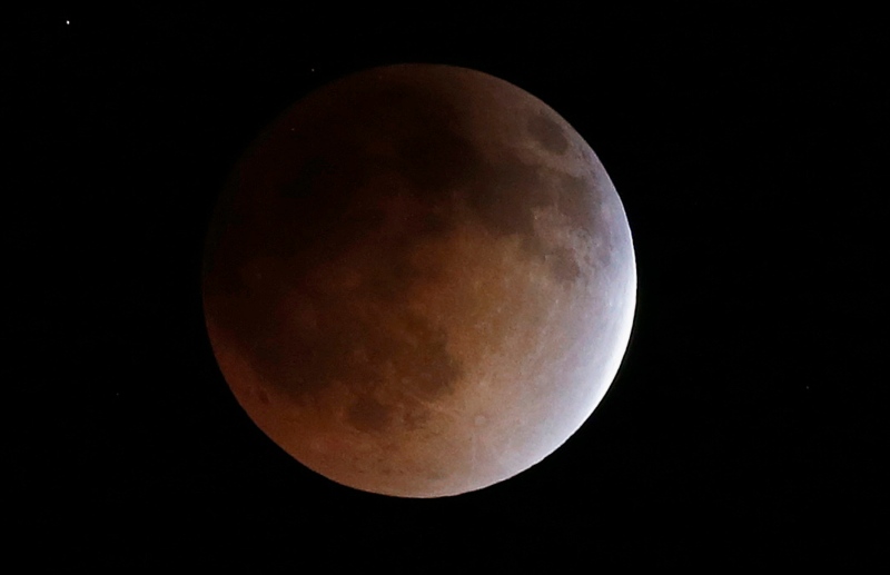 In this Tuesday, April 15, 2014 file photo, the moon turns an orange hue during a total lunar eclipse in the sky above Phoenix. On Wednesday morning, Oct. 8, 2014, North Americans will have prime viewing of a full lunar eclipse, especially in the West. The total eclipse will last an hour, until sunrise on the East Coast. (AP Photo/Ross D. Franklin, File)
