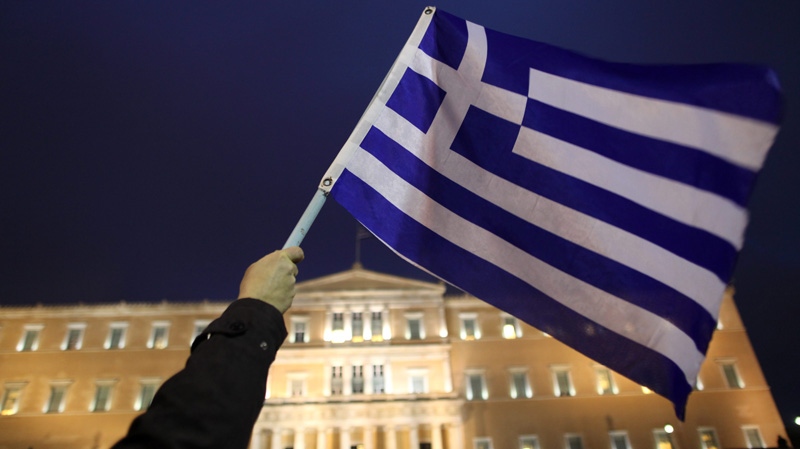 In this Feb. 22 2012 file photo, a protester waves a Greek flag in front of the parliament during a protest in Athens. (AP Photo/Petros Giannakouris)
