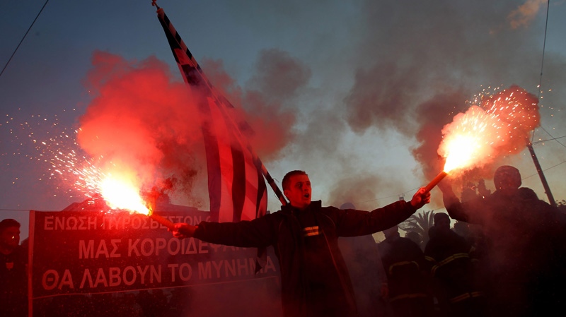A protesting firefighter holds a Greek flag and flares during a demonstration against the Greek government's austerity measures outside the Greek Parliament in Athens, on Tuesday, Feb. 28, 2012. (AP Photo/Petros Giannakouris)