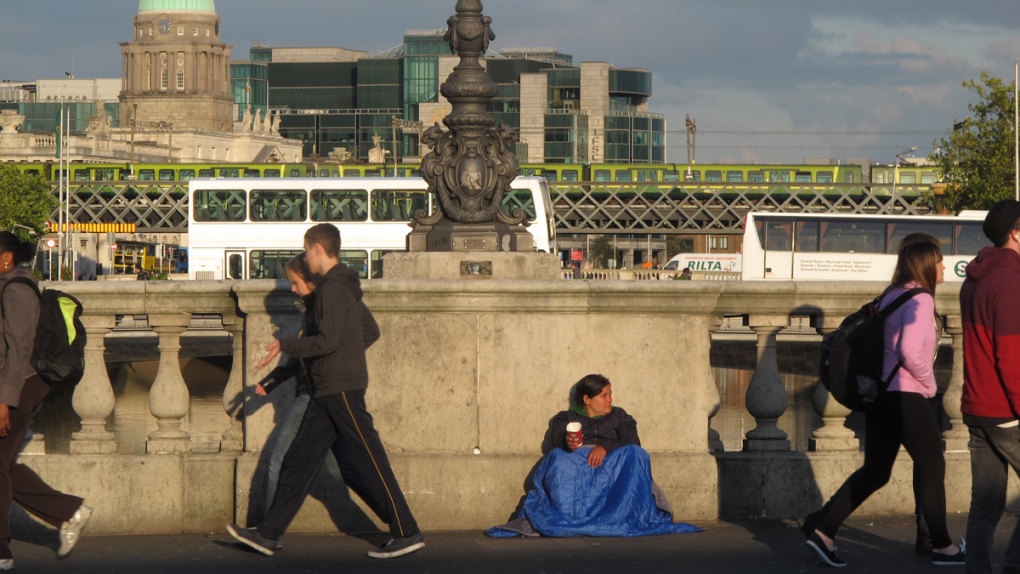 Pedestrians pass a beggar in Dublin, Ireland