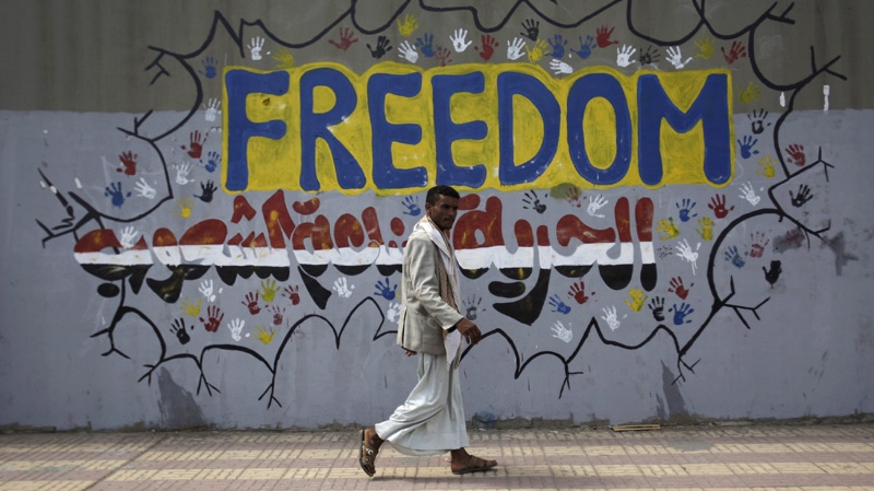 A Yemeni walks past a graffiti that reads "Freedom is made by people" on a street where protestors demanded the trial for the former President Ali Abdullah Saleh, in Sanaa, Yemen, Friday, March 2, 2012. (AP Photo/Hani Mohammed)
