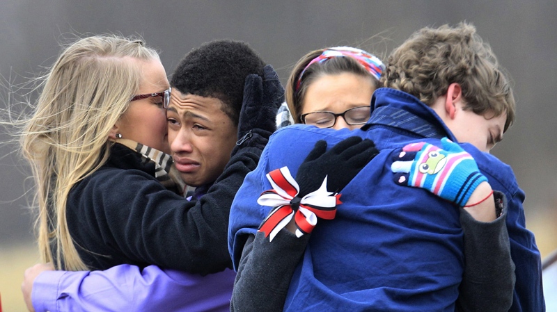 People hug after the burial of Daniel Parmertor at All Soul's Cemetery, Saturday, March 3, 2012, in Chardon, Ohio. Parmertor and two others were fatally shot Monday at Chardon High School. 