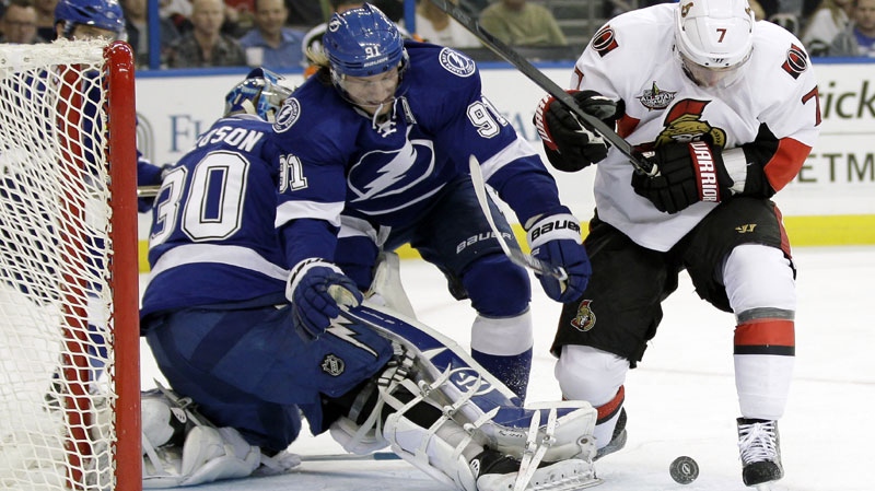 Ottawa Senators center Kyle Turris (7) works against Tampa Bay Lightning center Steven Stamkos (91) for a loose puck in front of Lightning goaltender Dwayne Roloson during the first period of an NHL hockey game Tuesday, March 6, 2012, in Tampa, Fla. (AP Photo/Chris O'Meara)