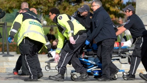 Paramedics and police pull a shooting victim away from the Canadian War Memorial in Ottawa on Wednesday, Oct.22, 2014. (The Canadian Press/Adrian Wyld)