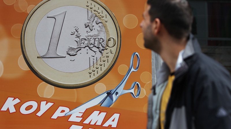 A pedestrian looks a sign in a shop reading: 'One euro, price haircut' in Athens on Thursday, March 8, 2012.(AP / Thanassis Stavrakis)