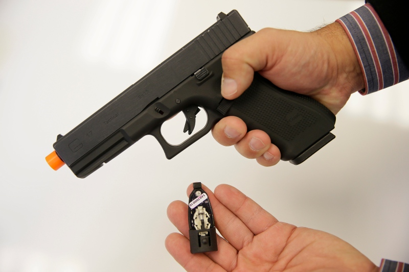 Jim Schaff, vice president of marketing with Yardarm, holds a sensor that fits into an Airsoft replica of a Glock 17 handgun in San Francisco on Oct. 22, 2014. (AP Photo/Eric Risberg)
