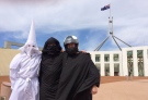 Three men wearing a Ku Klux Klan hood, a niqab and a motorcycle helmet pose for a photo outside Australia's Parliament House in Canberra, Monday, Oct. 27, 2014. (AP / Nick Folkes)