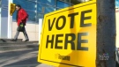 A woman walks past a voting sign in Toronto on Monday, Oct. 27, 2014. 