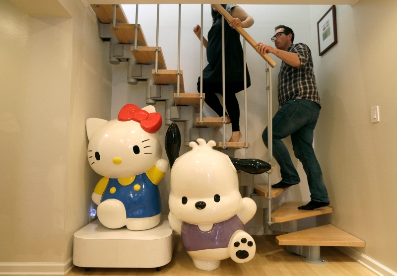 In this Oct. 13, 2014 photo, Salumeh Eslamieh, top left, and Marty Garrett walk up the stairs past statues of Sanrio characters Hello Kitty, bottom left, and Pochacco displayed at their home in San Francisco. (AP Photo/Jeff Chiu)