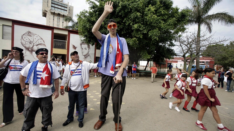 Sultan Kosen, center, 28, of Turkey, who according to the Guinness World Record Association is the world's tallest man, waves as he is accompanied by members of the newly-created Cuba Amore Foundation, during a visit to the Cesareo Fernandez school in Havana, Cuba, Monday, March 14, 2011. (AP Photo/Javier Galeano)