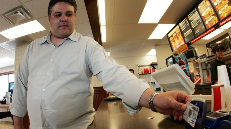 In this June 22, 2005 file photo, Chris Gallegos swipes his "blink" technology credit card across a reader on the counter at an east Denver fast food restaurant. (AP Photo/David Zalubowski)