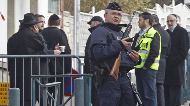An armed police officer stands guard at the entrance of the Ozar Hatorah Jewish school where a gunman opened fire killing four people in Toulouse, southwestern France, Tuesday, March 20, 2012. (AP Photo/Remy de la Mauviniere)