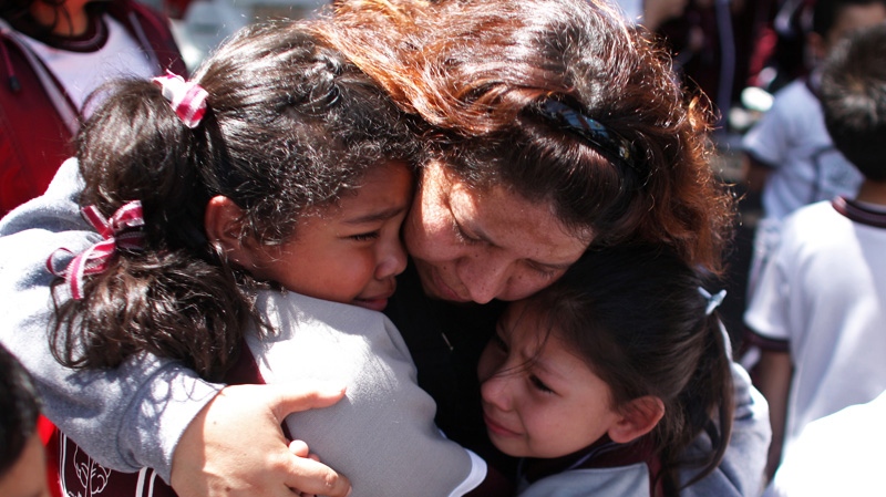 A woman comforts her children outside a school at the Roma neighborhood after a earthquake felt in Mexico City Tuesday March 20, 2012. (AP / Alexandre Meneghini)