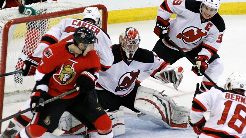 New Jersey Devils goaltender Johan Hedberg keeps his eye on the puck as teammate Zack Parisse (9) and Ryan Carter (20) Ottawa Senators' Kyle Turris (7) battle during third period NHL hockey in Ottawa on Tuesday March 20, 2012. The Devils beat the Senators 1-0. THE CANADIAN PRESS/Fred Chartrand
