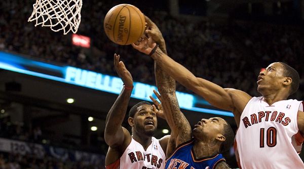 Toronto Raptors Amir Johnson, left, and DeMar DeRozan, right, vie for a rebound against J.R. Smith of the New York Knicks during second half NBA action in Toronto on Friday, March 23 2012. THE CANADIAN PRESS/Aaron Vincent Elkaim