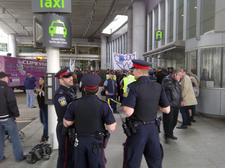 Police keep a close eye on Air Canada workers shortly before they were ordered to headed back to work at Pearson International Airport, Friday, March 23, 2012. (CTV News)  