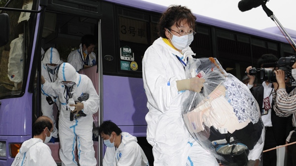In this May 10, 2011 file photo, villagers get off a bus after making a brief visit to their houses located near the Fukushima Dai-ichi nuclear power plant, in Kawauchi, Fukushima prefecture, northern Japan. (AP / Kyodo News, File)