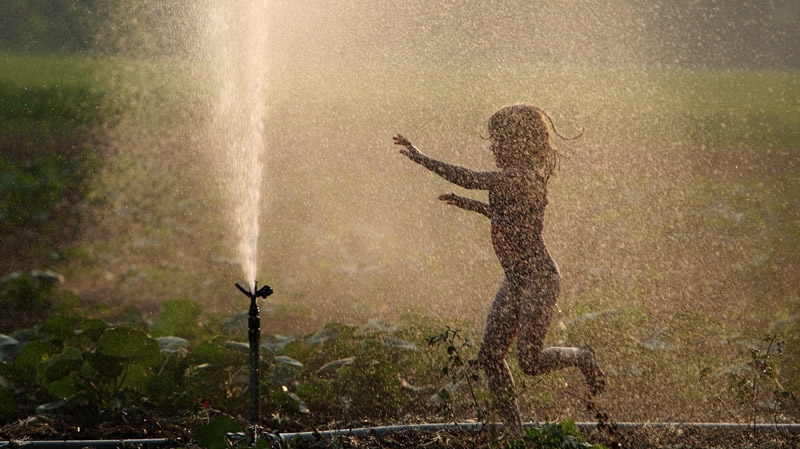 Anna Noorenberghe plays in the irrigation sprinkler on the family farm in Mt. Brydges, Ontario, west of London, as the sun sets on the first day of summer, Tuesday, June 21, 2011.