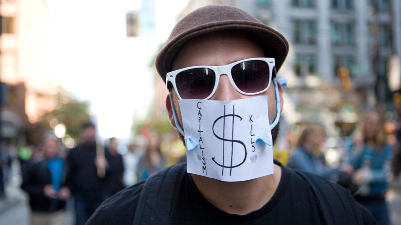In this Oct. 15, 2011 file photo, a masked protestor marches during the Occupy Vancouver group assembly in Vancouver. (THE CANADIAN PRESS/Geoff Howe)