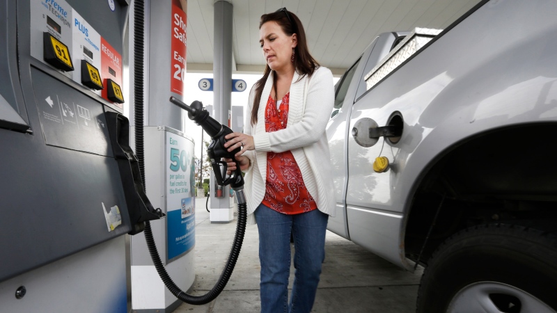 Lydia Holland replaces the gas nozzle after filling up at a gas station in Sacramento, Calif., Nov. 12, 2014. (AP / Rich Pedroncelli)