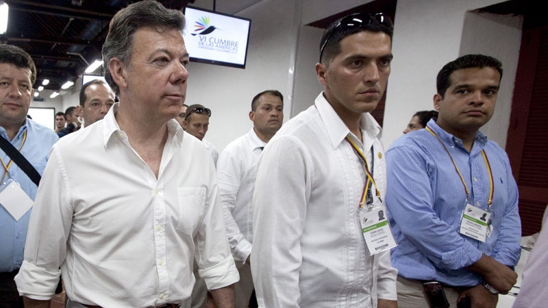 Colombia's President Juan Manuel Santos, left, visits the press room of the 6th Summit of the Americas in Cartagena, Colombia, Wednesday, April 11, 2012.