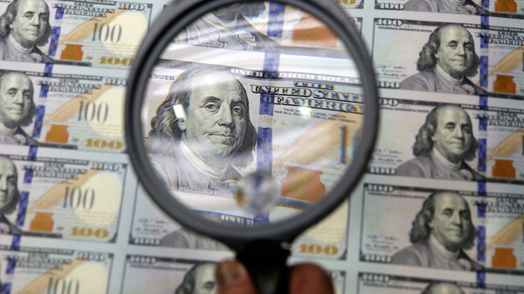 Inspecting a sheet of uncut $100 bills